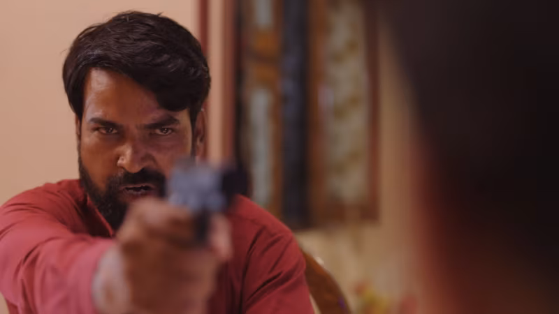 A man levels a pistol straight down the lens