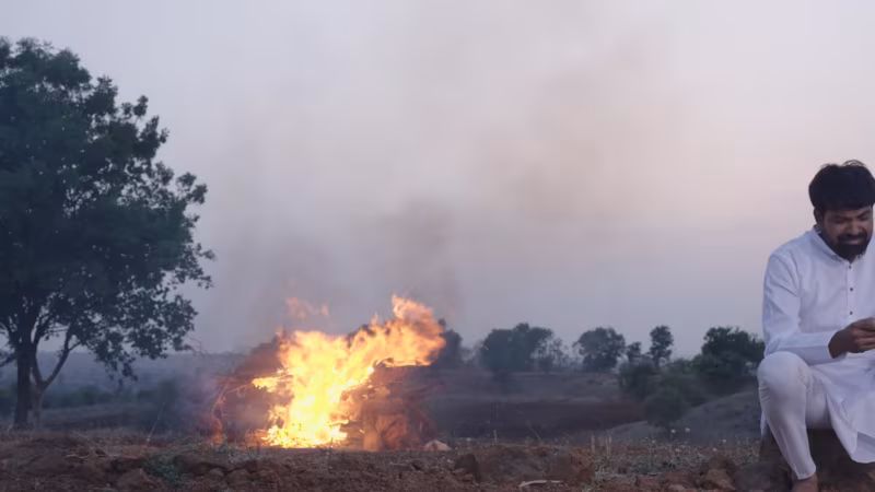The pyre burning in the open field, a son sitting apart from it