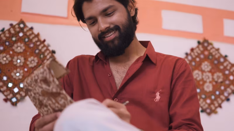 A still from Bahut Khoobsurat Ho Tum: a man in a red shirt smiling, a mirrored wall hanging behind him