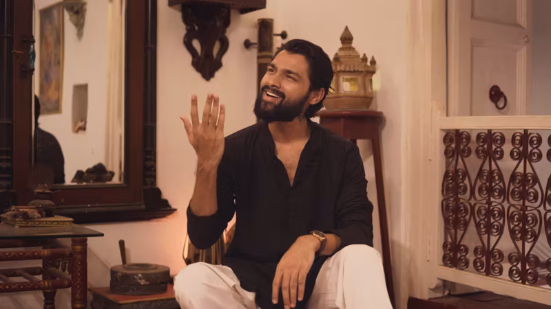A still from Bahut Khoobsurat Ho Tum: a man in a black kurta seated in a heritage room, mid gesture