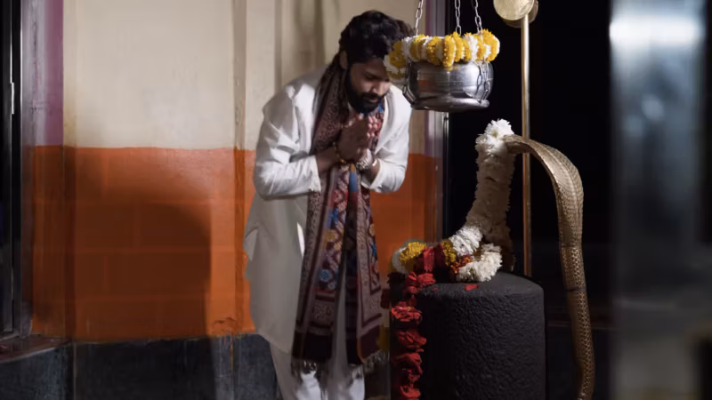 A still from Mere Dil Mein Bhole Baba: a man in white before a garlanded Shiva lingam