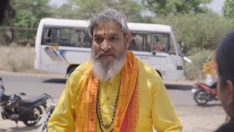 A sadhu in saffron beside the bus, talking to a young couple